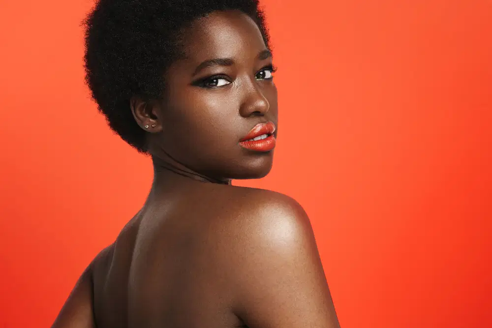 Imagem de mulher maquiada com olhar esfumado na cor preta e lábios com batom laranja