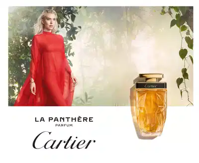 Mulher loira com vestido vermelho em cenário natural, promovendo perfume La Panthère da Cartier.