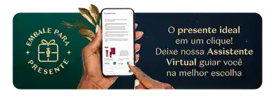 Mão segurando um smartphone com a tela da Assistente Virtual, sobre fundo verde e azul escuro e detalhes de folhas douradas. O texto convida a escolher o presente ideal em um clique.