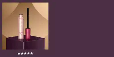 O banner apresenta uma embalagem de Máscara de Cílios em destaque, com um fundo desfocado em tons de marrom e roxo. A embalagem possui uma textura metálica e uma cor rosa vibrante, criando um visual elegante e sofisticado.