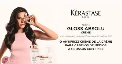 Kérastase Paris apresenta novo Gloss Absolu Crème com ácido hialurônico, ácido glicólico e rosa selvagem em óleo. Antifrizz creme de la crème para cabelos de médios a grossos com frizz. Mulher com cabelo castanho ondulado usando top rosa segura frasco de Eau de Parfum perto do rosto. Linha de produtos Kérastase exibida em embalagens brancas com detalhes dourados.