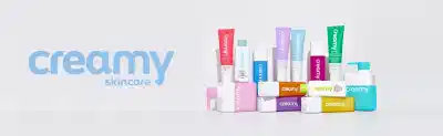 Coleção Creamy Skincare com diversos produtos de cuidados, incluindo tubos e potes em cores variadas como rosa, roxo, azul, verde, amarelo e branco, com rótulos identificando a marca Creamy em diferentes apresentações e embalagens.