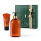 Caixa verde com detalhes dourados e dois itens da marca Casa 214 Vanilla Sublime, sendo uma bisnaga laranja com letras douradas e tampa preta de creme hidratante de mãos e um vidro laranja com bomba dosadora preta de sabonete líquido.