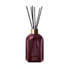 Frasco de vidro roxo com tampa dourada, varetas pretas e rótulo em letras douradas. O produto faz parte da linha Casa 214 Figo Magnífico e possui design elegante e sofisticado.