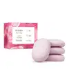 O produto apresentado é um conjunto de sabonetes vegetais da linha Instance Rosa Absoluta. A embalagem é uma caixa rosa com detalhes em branco, contendo 4 sabonetes vegetais de 80g cada. Os sabonetes em si possuem formato oval e coloração rosa clara.