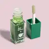 Frasco transparente contendo líquido verde e escova de aplicação em recipiente verde, com rótulo exibindo a frase "Quem disse, Berenice?".
