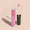 Frasco cilíndrico transparente contendo um brilho labial rosa brilhante. Rótulo na embalagem com o nome do produto "Gloss dos Sonhos" e a descrição "Quem disse, berence?". Ao lado, a tampa preta do produto, que acompanha um aplicador de espuma rosa.