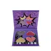 Paleta de sombras compacta da marca "The Powerpuff Girls" em embalagem roxa com ilustrações e texto, contendo sombras em tons de vermelho, rosa e dourado.