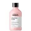 Frasco de plástico rosa com tampa preta. Rótulo com texto "L'OREAL PROFESSIONNEL PARIS Vitamino Color" e "SHAMPOOING PROFESSIONNEL". Produto de cuidados capilares para cabelos coloridos.