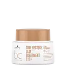 A imagem traz a máscara que vem em um pote branco com tampa bege de 200ml. Na embalagem, está escrito "Time Restore Clay Treatment Q10+" em letras marrons. Também está mencionado "Clean Performance".