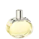 A imagem mostra o perfume Barénia de Hermès. Seu frasco é de vidro arredondado e transparente, permitindo ver o líquido amarelado em seu interior. Sua tampa é cilíndrica e prateada e possui uma aplicação com pinos em forma de pirâmide com facetas curvas.