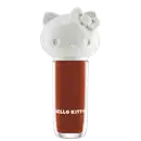 Maquiagem em formato cilíndrico com a cabeça da personagem Hello Kitty como tampa. A parte superior é branca com detalhes em relevo que representam os olhos, orelhas e laço da Hello Kitty. É possível ver a cor do produto pelo corpo transparente.