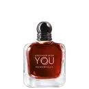 Frasco  e caixa do perfume com formato esférico e tampa prateada. O líquido vermelho exibe o texto "STRONGER WITH YOU POWERFULLY" em letras brancas. O produto é apresentado em fundo preto, destacando sua aparência elegante e sofisticada.