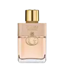 Frasco de perfume Guess Iconic, com embalagem em tons de bege e dourado, contendo o logotipo da marca em destaque. O frasco possui formato cilíndrico com tampa dourada, transmitindo uma imagem elegante e sofisticada.