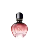 Perfume em frasco de vidro arredondado com tampa preta e detalhes dourados. O frasco é rosa translúcido, com o nome "PURE XS" impresso em letras douradas na parte frontal. A embalagem tem um formato elegante e sofisticado.