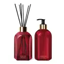 Dois vidros vermelhos da marca Casa 214 Gardênia Imperial: um difusor de ambientes com varetas e o outro com bico dosador preto contendo sabonete líquido.