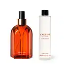 Imagem de dois produtos da marca Casa 214, sendo um vidro laranja com detalhe dourado e borrifador preto e uma embalagem refil de aromatizador de ambientes em frasco transparente, líquido claro, tampa preta e rótulo escrito Vanilla Sublime.
