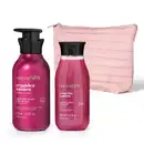 Dois itens de perfumaria da marca Nativa SPA Orquídea Lumiere: um creme desodorante corporal pink em frasco com bomba pump preta e um sabonete líquido perfumado em frasco pink com tampa preta, acompanhados de um necessaire rosa clara acolchoada.