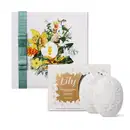 Caixa branca com ilustração floral colorida, contendo dois sabonetes em barra perfumados com fragrância de lírio, embalados em caixa com detalhes dourados e florais.