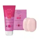 Conjunto de produtos de corpo e banho da marca Cuide-se Bem Cereja Livre, incluindo bisnaga de loção corporal bicolor de rosa claro e rosa escuro com tampa branca, dois sabonetes em barra rosa claro e sua caixa rosa ao lado deles.