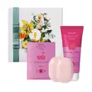 Sabonetes, creme hidratante e desodorante, em embalagens com cores rosa e verde, com rótulos e ilustrações de flores.
