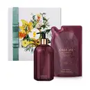 Kit contendo um sabonete líquido da marca Casa 214 Figo Magnífico, com frasco de vidro de cor vinho, pump dourado e preto e rótulo dourado, acompanhado de refil em embalagem plástica nas mesmas cores, além de uma caixa com ilustração floral.