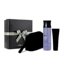 Caixa preta com laço verde centralizado. Ao lado frasco de item de perfumaria cilíndrico na cor lilás com tampa preta da linha Nativa Spa Lilac e outros dois itens misteriosos, dos quais só se vê a silhueta.