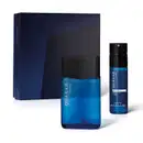 Imagem de dois produtos da marca Quasar Classic, sendo um vidro de desodorante colônia e um frasco de body splash, sendo as duas embalagens na cor azul com tampa preta e rótulo amarelo, acompanhado de uma caixa com ilustrações geométricas em tons de azul.