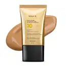 Imagem do tubo de base líquida protetora Make B. Hyaluronic Cor 50. Ele é dourado, possui tampa preta e informações em letras pretas e laranja. Atrás da embalagem está a textura do produto, mostrando sua intensidade e a real cor da base.