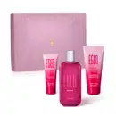 Caixa rosa com flores em relevo e três itens da marca Egeo Dolce, sendo uma bisnaga de creme hidratante para as mãos, outra de loção hidratante corporal e um vidro com tampa prateada contendo desodorante colônia.