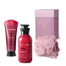 Caixa roxa com detalhe dourado, esponja de banho roxa e dois produtos Nativa SPA Ameixa, sendo uma bisnaga de sabonete líquido corporal e um frasco de loção nutritiva desodorante, ambos em embalagem rosa vibrante com tampa preta.