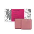 Imagem de uma caixa com faixa rosa e ilustrações em preto e branco de folhas e flores, contendo dois sabonetes em barra de cor rosa com formato quadrados. O produto é da marca Nativa SPA Ameixa Plum.