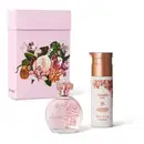 Imagem do kit de presente Floratta Rose, com o clássico vidro transparente do desodorante colônia e um frasco branco creme hidratante corporal, além de uma caixa com estampa floral. As embalagens trazem flores e tampas douradas.