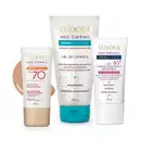 Três produtos da linha Neo Dermo da Eudora: protetor solar facial FPS 70, gel de limpeza e creme hidratante antissinais 45+, em embalagens brancas e azuis com detalhes dourados.