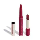 O produto apresentado na imagem é um batom da marca Niina Secrets Eudora, de tom marrom avermelhado fechado. São dois produtos em um: uma lapiseira delineadora com a ponta afiada e o batom em formato stick, com embalagem também rosa e detalhes dourados.
