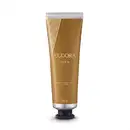 Tubo dourado com rótulo "Eudora Diva" contendo creme hidratante para mãos. Embalagem com listras diagonais douradas e brancas. Se trata de um produto de cuidados pessoais.