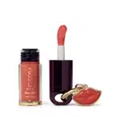 O produto de beleza Eudora Make apresenta um frasco de tinta labial na cor coral e um batom vermelho em embalagem preta com detalhes dourados, além de um pingente em formato de lábios.