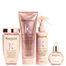 Produtos Kérastase em embalagens rosa e bege, incluindo shampoo, condicionador, spray e sérum para cabelos. As embalagens apresentam o logotipo da marca e informações sobre os benefícios dos produtos, como redução do frizz e brilho.