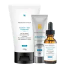 Kit SkinCeuticals com três produtos: gel de limpeza 120g, protetor solar FPS 80 40g e sérum defense 30ml. Embalagens brancas, cinzas e frasco âmbar com aplicador conta-gotas.