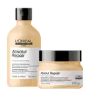 Imagem mostra um shampoo e uma máscara da linha Absolut Repair da L'Oréal Professionnel. O shampoo vem em um frasco plástico e a máscara em um pote bege com tampa preta. Ambos os produtos são amarelo claro.
