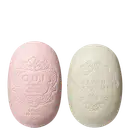 Dois sabonetes O.U.i em formato oval com relevos decorativos. À esquerda, sabonete rosa com inscrição "O.U.i Original Unique Individuel" e "Savon Parfumé 90g". À direita, sabonete bege com texto "Savon Parfumé 90g".