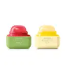 Imagem de duas embalagens de balm labial da marca Cuide-se Bem Feira Quem Disse, Berenice?, uma na cor verde com tampa rosa e sabor de melancia  e outra na cor branca com tampa amarela e sabor de banana.