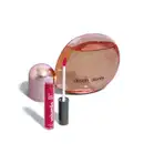 Frasco de perfume Desobediente da marca Quem Disse, Berenice? com tampa rosada e líquido vermelho, acompanhado de um batom líquido da mesma marca na cor rosa.