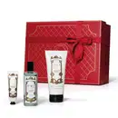 A imagem mostra um conjunto de produtos O.U.i em frente a uma bela caixa de presente vermelha. Ela traz um frasco com eau de parfum e dois tubos brancos com tampa preta, um menor com hidratante para as mãos e outro maior com hidratante para o corpo.