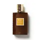 Frasco de item de perfumaria da marca O.U.i. com formato retangular, tampa dourada e rótulo com texto em amarelo e marrom sobre fundo marrom escuro.