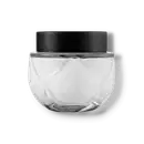 Frasco de vidro transparente arredondado com tampa preta. O recipiente tem uma forma esférica achatada. A tampa preta opaca contrasta com o vidro transparente do frasco que contém o creme na cor branca.