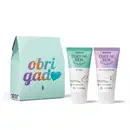 Caixa de presente azul com agradecimento em letras coloridas e dois tubos de creme para mãos da marca Cuide-se Bem, sendo um azul e branco com nuvem ilustrada da linha Nuvem, e um lilás e branco com flor de algodão ilustrada da linha Rosa e Algodão.