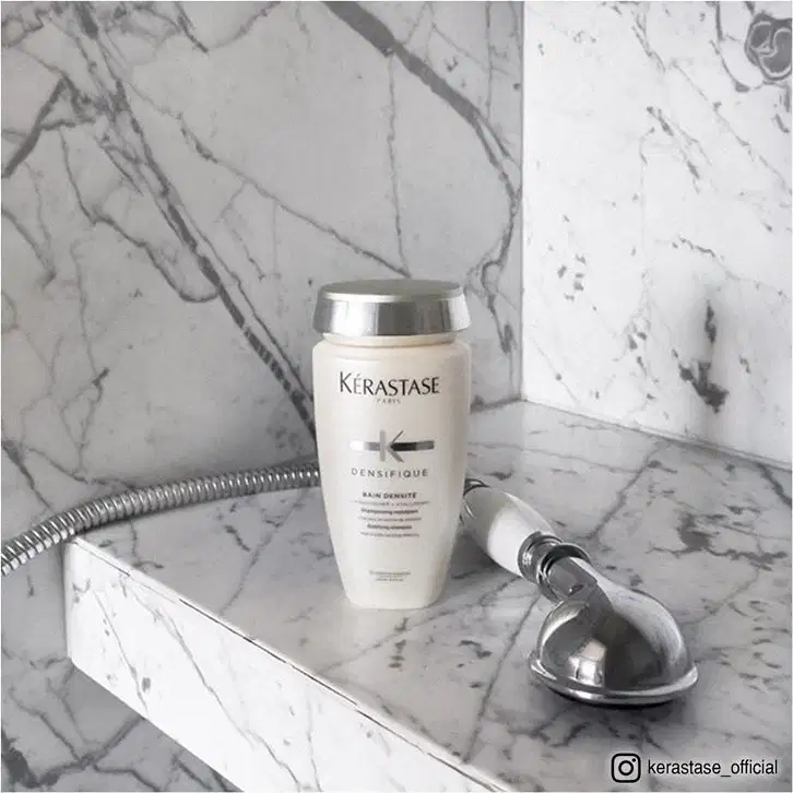 Dois produtos da marca Kérastase: um frasco de shampoo Bain Densité e um tubo de condicionador Fondant Densité, ambos em embalagens brancas e prateadas com o logotipo da marca.