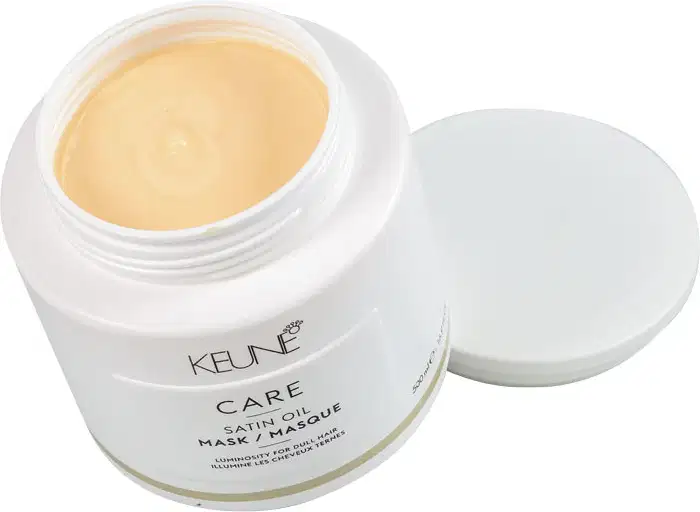Frasco branco com rótulo da marca Keune, contendo máscara de óleo de seda para cabelos opacos, com informações sobre luminosidade e tratamento para cabelos.