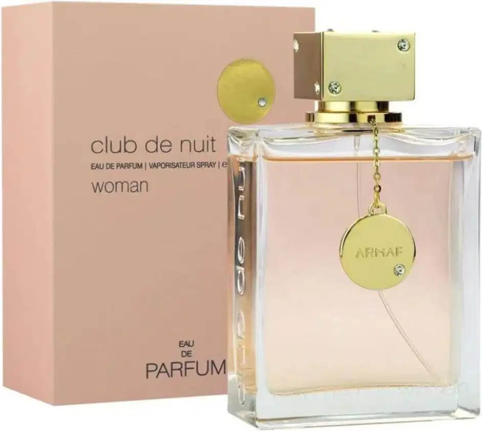 Frasco de perfume feminino da marca Armaf, chamado "Club de Nuit Woman", com embalagem rosa clara e detalhes dourados. O frasco possui um pingente dourado com o logotipo da marca.